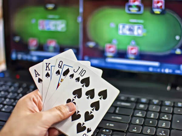 a person showing his cards in front of a laptop screen